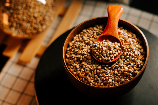 Fresh organic green buckwheat groats in a rustic wooden bowl with a measuring spoon