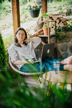 Freelance lifestyle: Smiling young woman typing on a laptop notebook outdoors on a bright summer day.