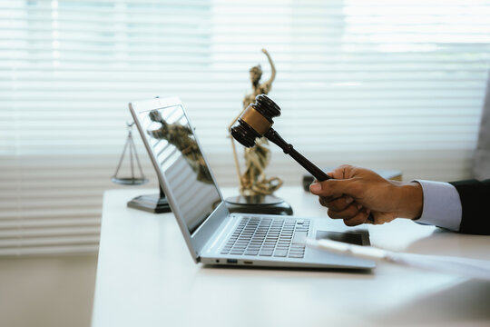A legal professional works on a laptop beside justice symbols and documents, representing legal consultation, contract review, compliance, digital law services, and business governance.