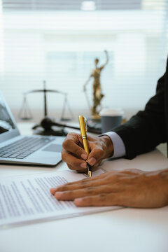 A lawyer reviews and signs legal documents at a modern office desk, symbolizing contract agreements, legal consultation, compliance, business law, and professional legal services.