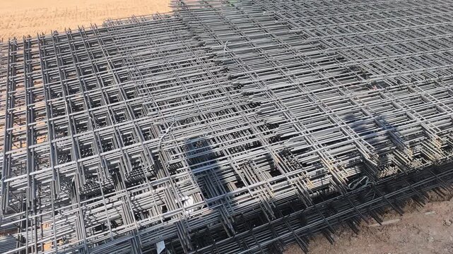 Steel BRC wire mesh laid on a construction site. Used for workers prepare the reinforcement for a concrete floor slab. This mesh ensures structural integrity and durability.