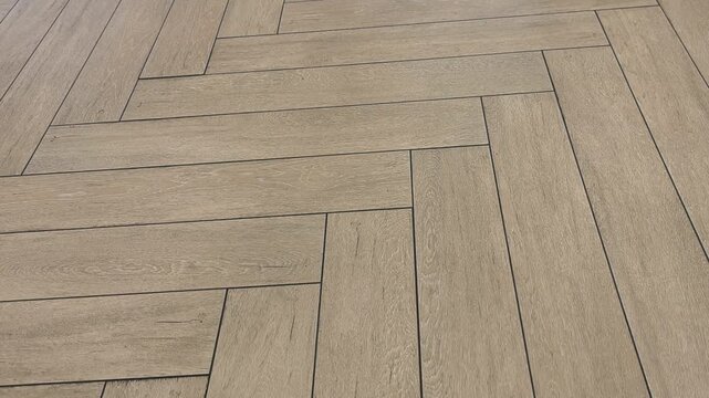 Elegant brown ceramic floor tiles are meticulously arranged in a classic herringbone pattern. The camera smoothly pans across the textured surface, highlighting the sophisticated interior design.