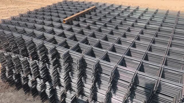 Steel BRC wire mesh laid on a construction site. Used for workers prepare the reinforcement for a concrete floor slab. This mesh ensures structural integrity and durability.