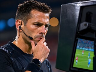 Fototapeta premium Focused soccer referee looking at var monitor during stadium football game