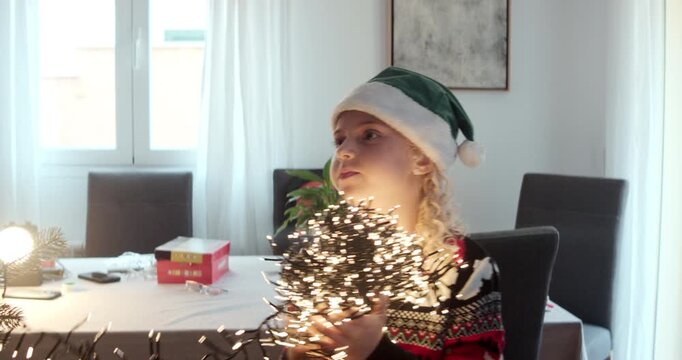 Cute girl untangling lights for Christmas tree decoration