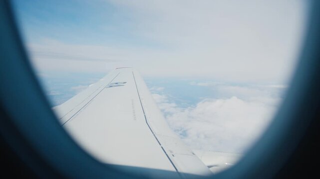 Beautiful view of slowly floating white clouds outside through airplane window. Airplane trip in summer vacation and holidays, enjoy safety and comfortable flight by airlines, traveling and tourism