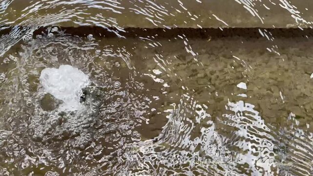 Close-up of a tiny fountain is bubbling up above the water, creating ripples on the surface.