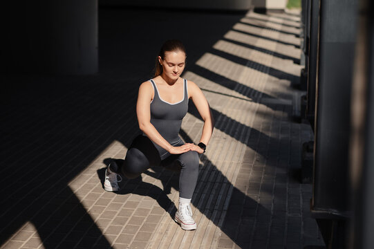 Woman performing a lunge exercise outdoors with dramatic shadows and