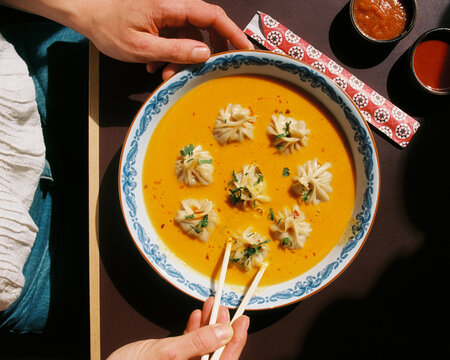 Person eating dumplings in soup from a bowl in a Himalayan restaurant