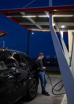 Man using his smartphone while charging electric car