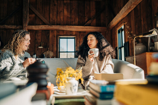 Two women chatting over coffee in a cozy rustic cabin