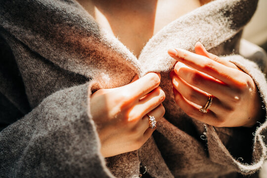 Woman hands wearing diamond rings closing coat