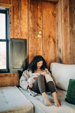 Mother breastfeeding baby in cozy rustic cabin home