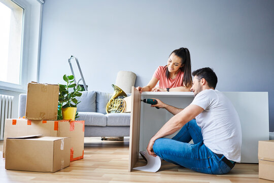 Couple in new apartment assembling furniture together