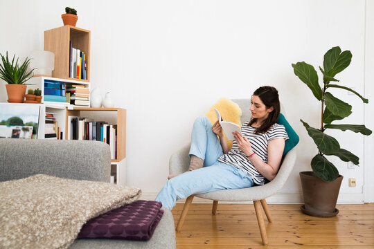 Woman at home sitting on chair reading book