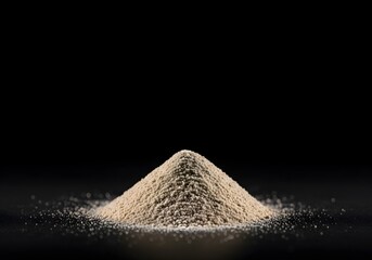 A fine powdery substance, appearing as a small peak of granular material, is artfully presented against a profoundly dark, velvety expanse, evoking a sense of natural texture and earthy