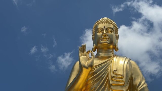 Pagoda roof decorated with Dharma wheel symbol above temple structure against blue sky with clouds. Sacred architecture.