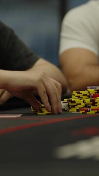 A close-up shot of a hand stacking poker chips on table