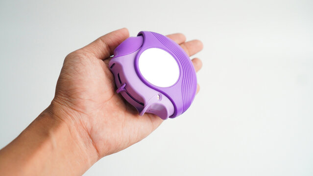 Hand holding medicine dry powder inhaler on grey background. Pharmaceutical product is used to lung inflammation and prevent asthma attack. Asthma and COPD concept.