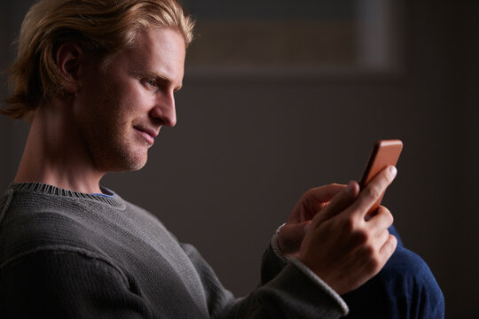 Night, reading or man with phone in house, browsing social media or connectivity for internet video. Smile, ebook or person with mobile for evening texting, web chat or forum for message notification