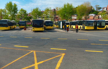 Obraz premium Public transportation buses parked at a bus station terminal in Istanbul, Turkey, with city buildings and mosque minarets visible under a clear blue sky during daytime.