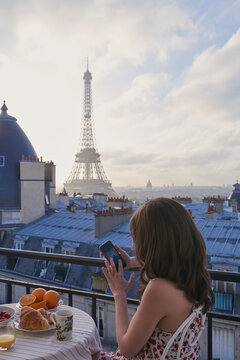 Breakfast, Eiffel Tower and phone with woman on balcony of hotel for holiday, travel or vacation. App, coffee and food with tourist person on terrace of accommodation for sightseeing in Paris