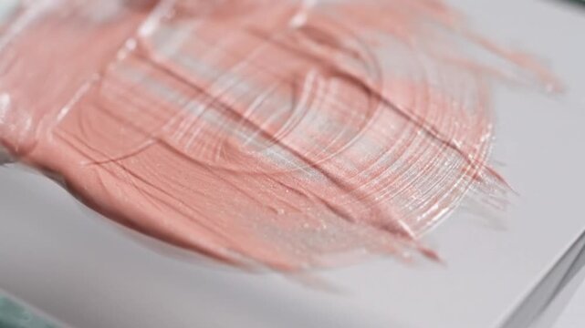 Macro close up of liquid foundation texture smeared with a spatula, pinkish beige cosmetic cream swatch for makeup product commercial.