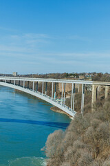 Fototapeta premium Visitors enjoy views of Niagara Falls from the Rainbow Bridge connecting the United States and Canada in clear weather during the day