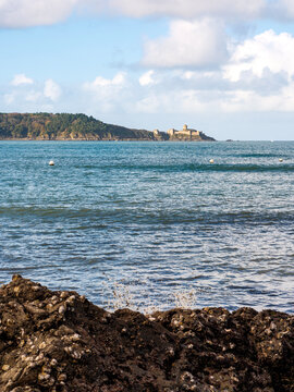 une vague explose sur un rocher devant le ch&acirc;teau