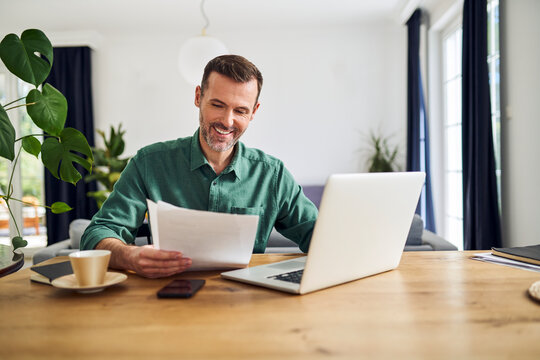 Confident businessman doing paperwork sitting at table working from home
