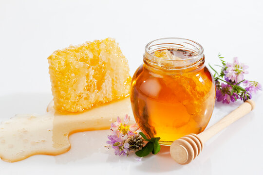 Glass of honey, honeycomb, honey spoon and wild flowers