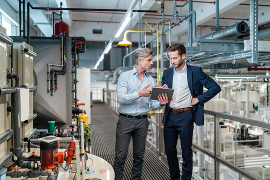 Two businessmen with tablet talking in a modern factory