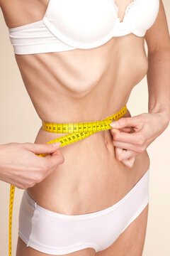 Anorexic young woman measuring her waist