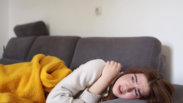 Young woman lying on sofa overwhelmed by seasonal depression and emotional exhaustion while struggling with apathy low energy and declining mental wellbeing during colder months