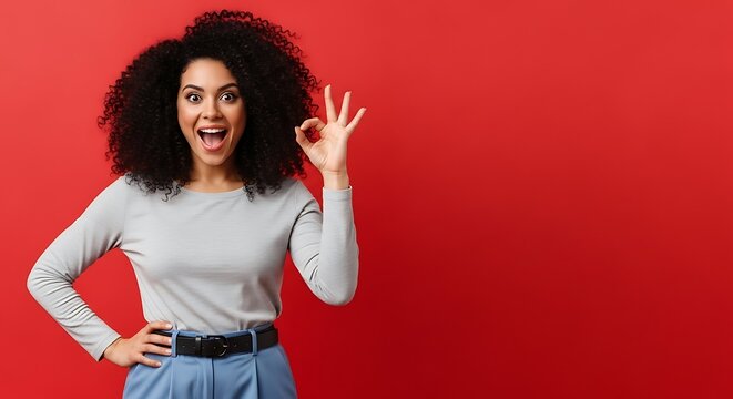 Happy woman with curly hair showing ok gesture against red background