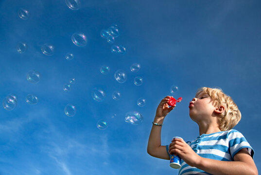 Germany, Bavaria, Boy (4-5 Years) blowing soap bubbles