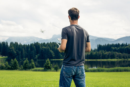 Germany, Bavaria, Pfronten, young man flying his drone at lakeside