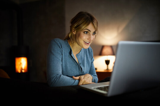 Portrait of amazed woman using laptop at home in the evening