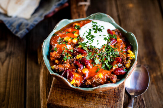 Chili con carne with kidney beans and corn, sour cream, parsley, tortilla bread