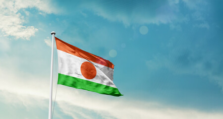 Niger national flag fluttering. The flag blowing in beautiful soft sky. Niger national flag for independence day. © Muhammad Arif