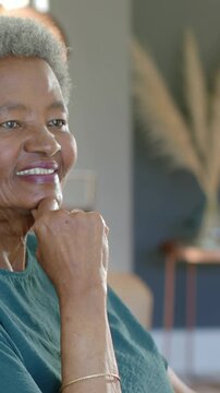 Vertical video: Resting chin, senior woman reacting to sun, tracking offscreen at home, green top
