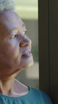 Vertical video: Gazing woman responding to light, making head, eye and lip moves at window teal top