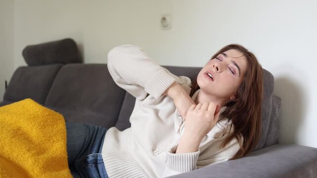 Young woman suffering from seasonal autumn illness while resting on sofa with headache fever and body weakness during cold weather home recovery concept