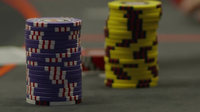 A close-up shot of a hand stacking blue poker chips