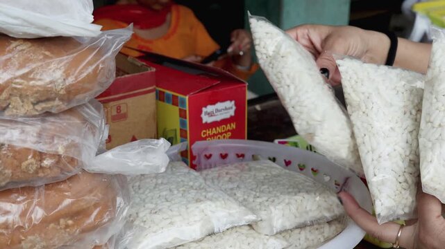 Close up video footage of hands selecting puffed rice prasad packets and religious food offerings for Hindu worship rituals in Uttarakhand India.