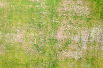 Top down perspective of a patchy green and brown playing field The Concept of outdoor recreation and decay © VicVaz