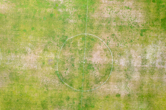 Top down perspective of a patchy green and brown playing field The Concept of outdoor recreation and decay