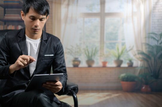 Thoughtful Young Man Using Tablet in Cozy Indoor Environment