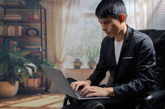 Young Man in Modern Office Typing on Laptop in Bright Living Space