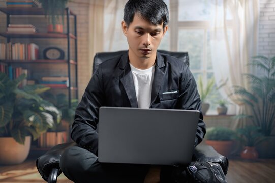 Focused Young Man Working on Laptop in Cozy Modern Living Room
